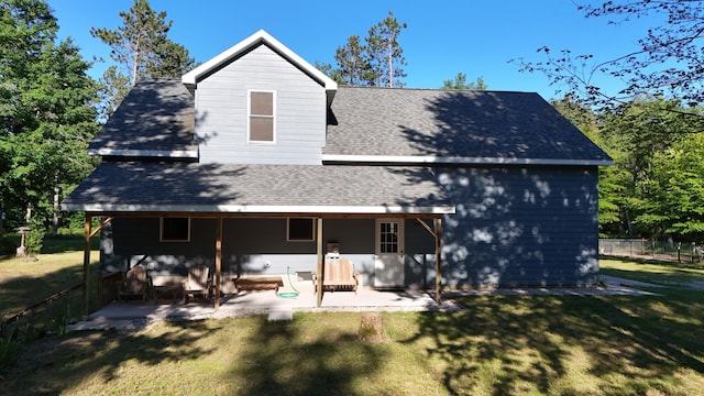 rear view of house featuring a patio, a shingled roof, a lawn, and fence