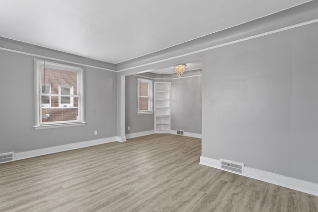 spare room featuring visible vents, baseboards, and wood finished floors