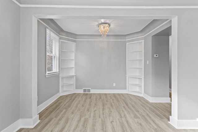 unfurnished room with built in shelves, wood finished floors, visible vents, and baseboards