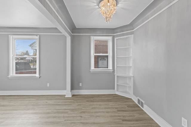 unfurnished room featuring baseboards, visible vents, a chandelier, and wood finished floors