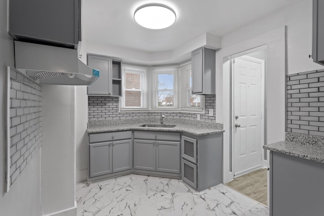 kitchen featuring decorative backsplash, marble finish floor, a sink, and gray cabinetry