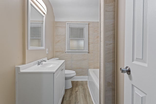 bathroom featuring toilet, vanity, wood finished floors, a tub, and walk in shower