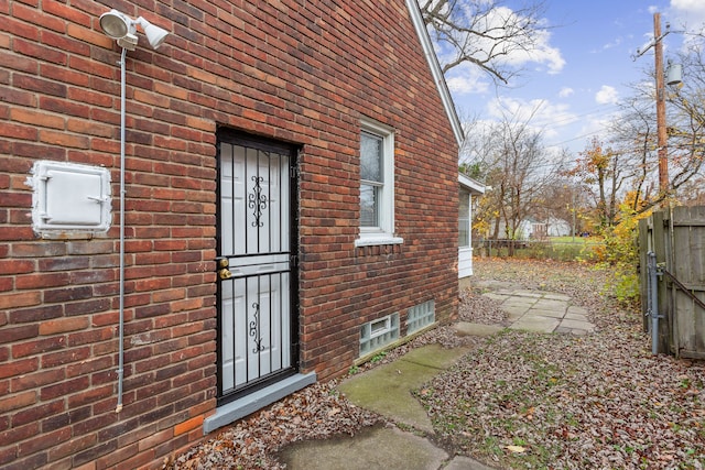 entrance to property featuring fence and brick siding