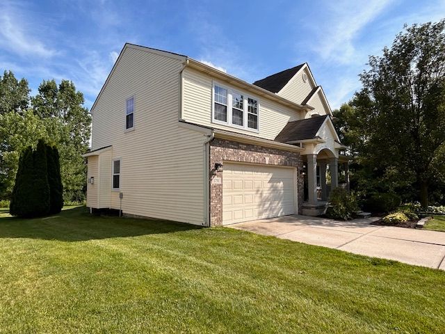 view of side of home with concrete driveway, a lawn, and brick siding