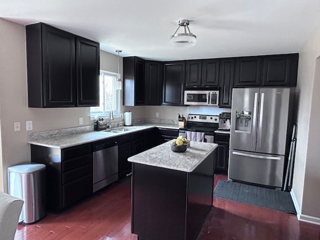 kitchen featuring dark cabinets, stainless steel appliances, dark wood-type flooring, a sink, and a kitchen island