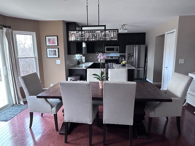 dining area with baseboards and dark wood-type flooring