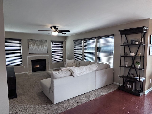 living room with baseboards, a premium fireplace, a ceiling fan, and wood finished floors