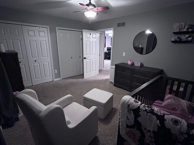 bedroom featuring carpet floors, multiple closets, visible vents, a ceiling fan, and baseboards