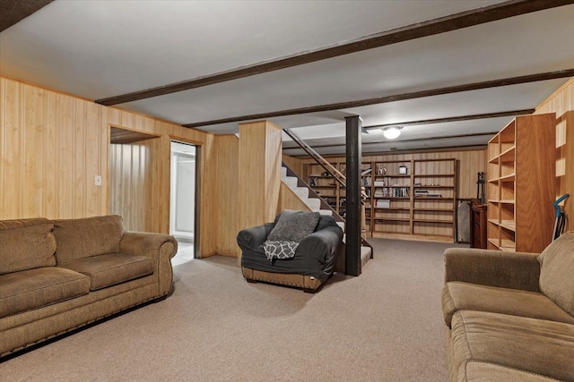 living room featuring wood walls, carpet, stairs, and beam ceiling