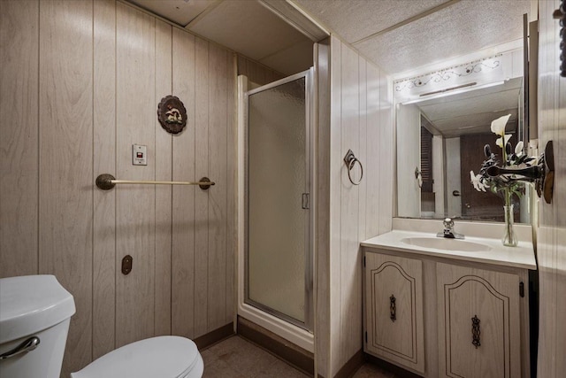 bathroom with vanity, wood walls, a shower stall, and toilet