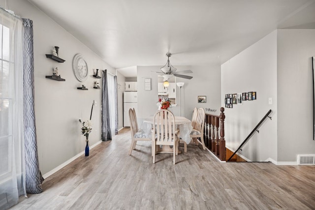 dining area with ceiling fan, light wood-style flooring, visible vents, and baseboards