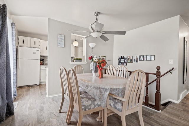 dining space with baseboards, a ceiling fan, and light wood-style floors