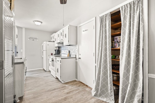 kitchen featuring white appliances, white cabinets, light wood-type flooring, under cabinet range hood, and backsplash