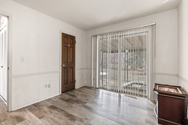 interior space with wainscoting, plenty of natural light, and wood finished floors