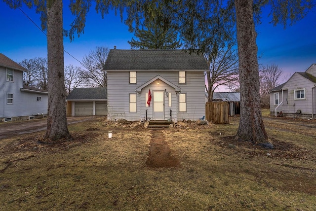 view of front facade with a garage, roof with shingles, and fence