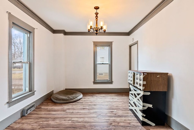 interior space with baseboards, crown molding, an inviting chandelier, and wood finished floors