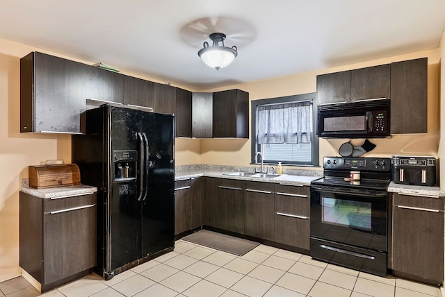 kitchen featuring dark brown cabinetry, light tile patterned floors, light countertops, black appliances, and a sink