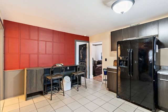 kitchen with light tile patterned floors, light countertops, black refrigerator with ice dispenser, and red cabinetry