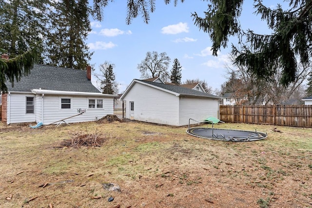 back of property with a trampoline, fence, and a lawn