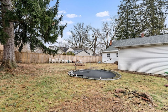 view of yard with a trampoline and fence