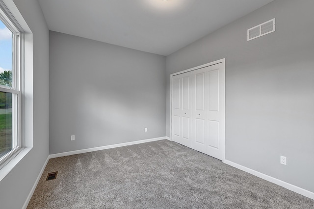 unfurnished bedroom featuring a closet, carpet, visible vents, and baseboards