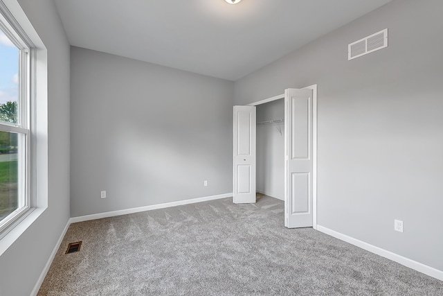 unfurnished bedroom with carpet floors, baseboards, and visible vents