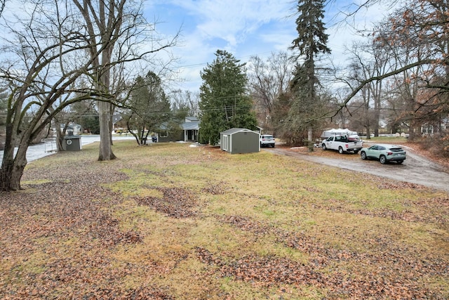 view of yard with driveway, a shed, and an outdoor structure