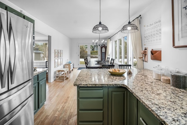 kitchen featuring a healthy amount of sunlight, light wood-style flooring, green cabinets, and freestanding refrigerator