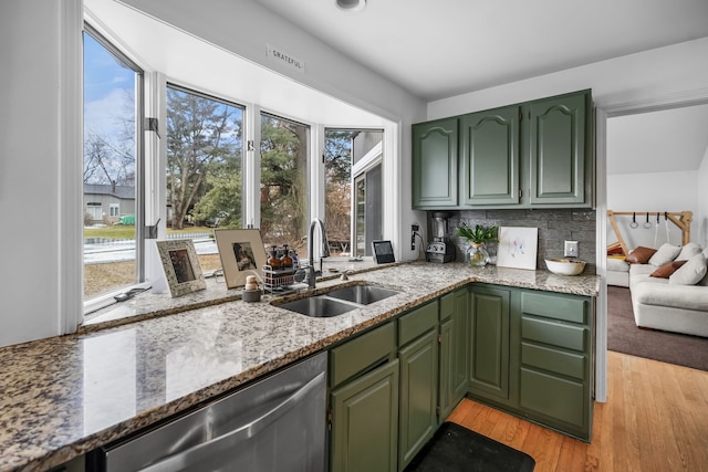 kitchen featuring light stone counters, a sink, light wood-style floors, stainless steel dishwasher, and green cabinetry