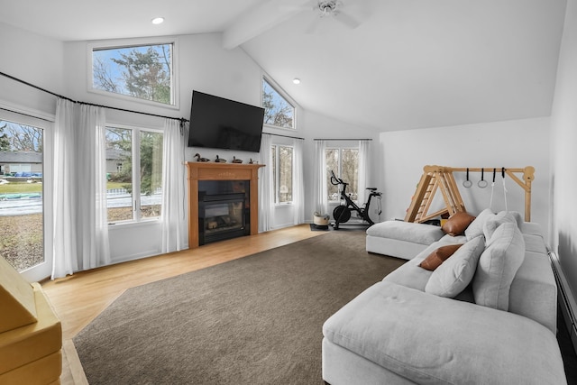 living area featuring a glass covered fireplace, wood finished floors, high vaulted ceiling, beam ceiling, and recessed lighting