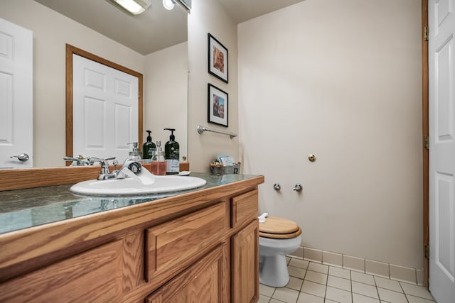 half bath with tile patterned flooring, baseboards, vanity, and toilet