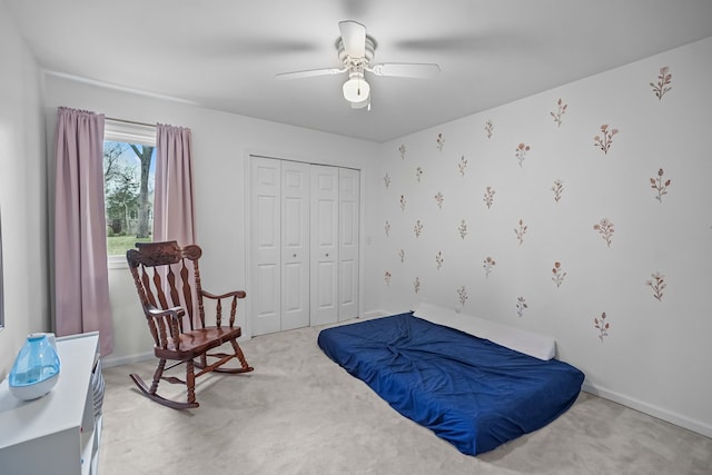 bedroom with light carpet, baseboards, a ceiling fan, and a closet