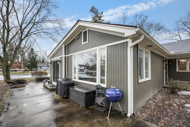 view of home's exterior with a patio area and roof with shingles