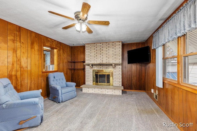 living area featuring ceiling fan, wood walls, a fireplace, visible vents, and carpet