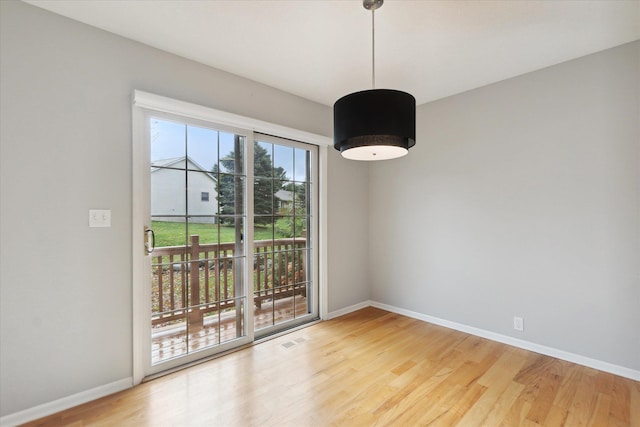 empty room featuring light wood-style floors, visible vents, and baseboards