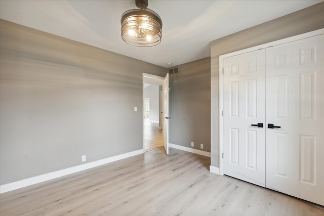 unfurnished bedroom featuring a closet, light wood-type flooring, visible vents, and baseboards