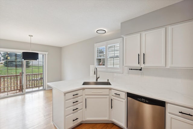 kitchen with dishwasher, a peninsula, a sink, and white cabinetry