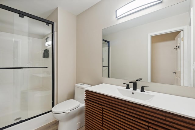 bathroom with toilet, a stall shower, and vanity