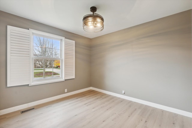 spare room with light wood-style floors, visible vents, and baseboards