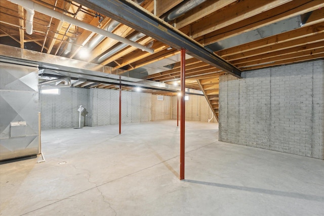 unfinished below grade area featuring heating unit and brick wall