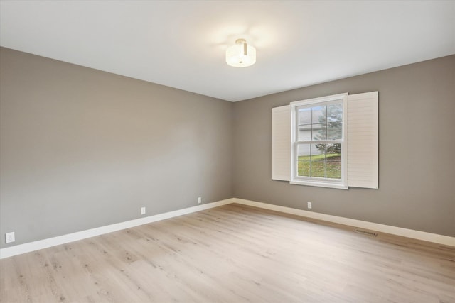 spare room featuring light wood-style floors, visible vents, and baseboards