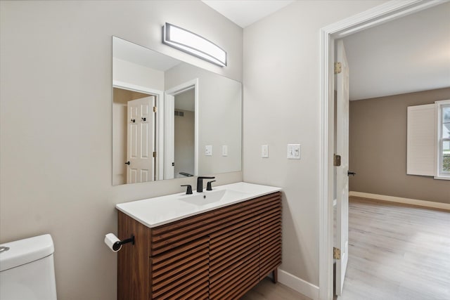 bathroom with baseboards, vanity, toilet, and wood finished floors