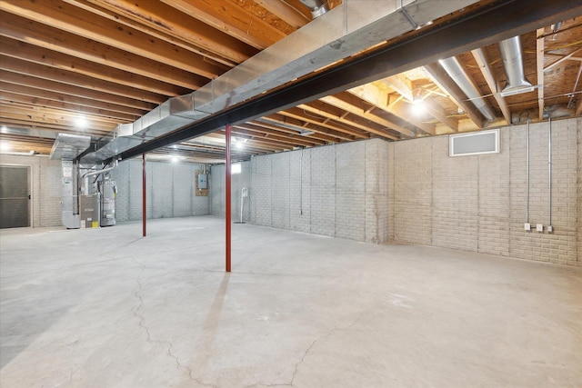 unfinished basement with brick wall, water heater, and heating unit