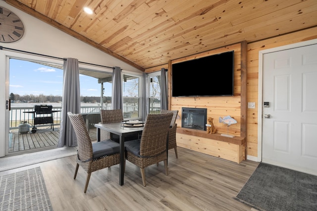 dining area with lofted ceiling, light wood-style floors, wood ceiling, and wooden walls