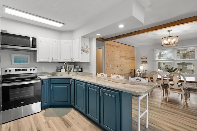 kitchen featuring appliances with stainless steel finishes, a kitchen breakfast bar, blue cabinets, white cabinetry, and a sink