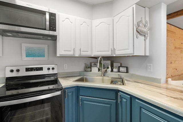 kitchen with blue cabinets, white cabinets, stainless steel appliances, and a sink