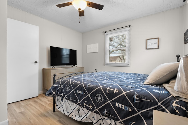 bedroom with a textured ceiling, a ceiling fan, and wood finished floors