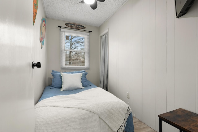 bedroom with light wood-style flooring, ceiling fan, and a textured ceiling