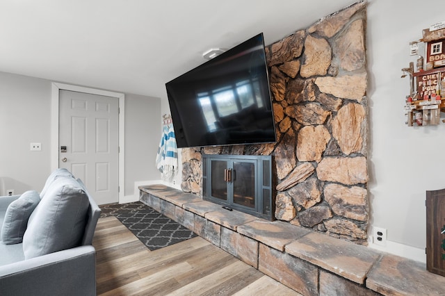 living room featuring a fireplace, baseboards, and wood finished floors