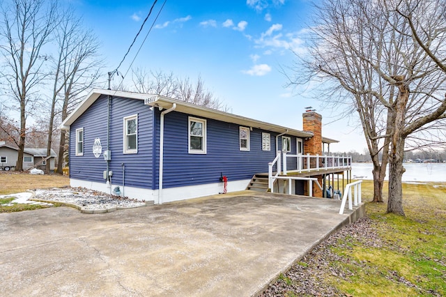 exterior space with driveway, stairs, a chimney, and a wooden deck